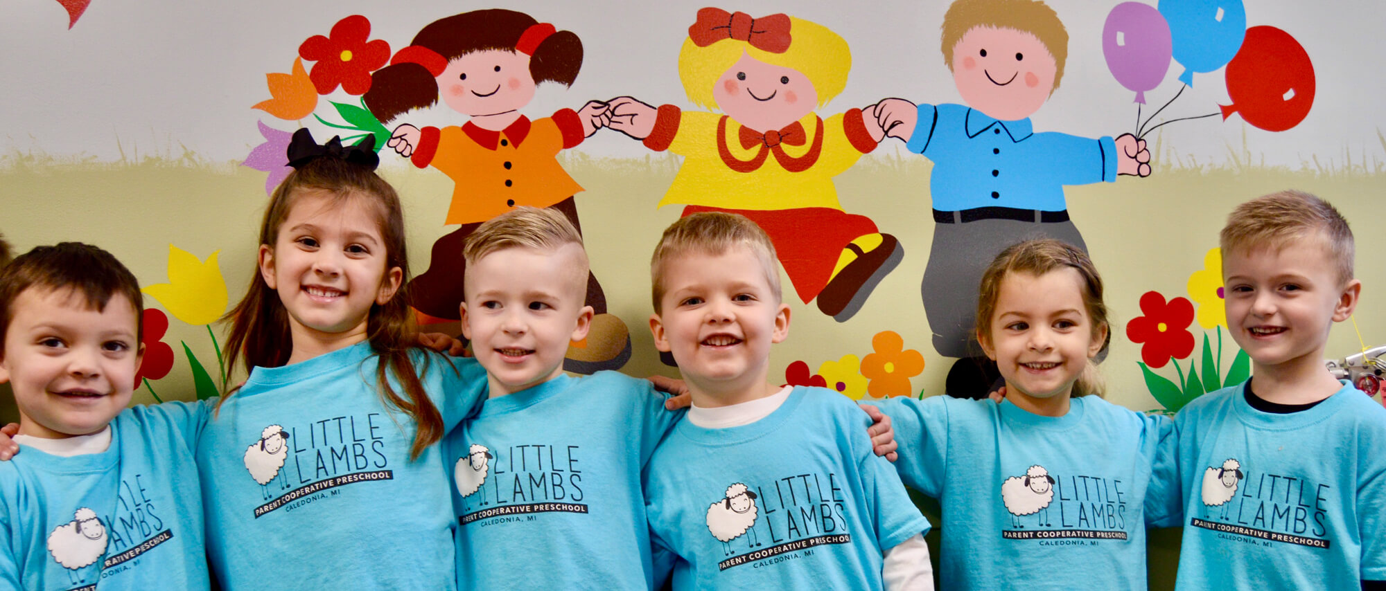 Smiling children wearing Little Lamb tee shirts