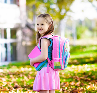 little girl wearing her backpack and carrying books 