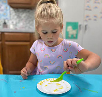 child painting with fork on plate
